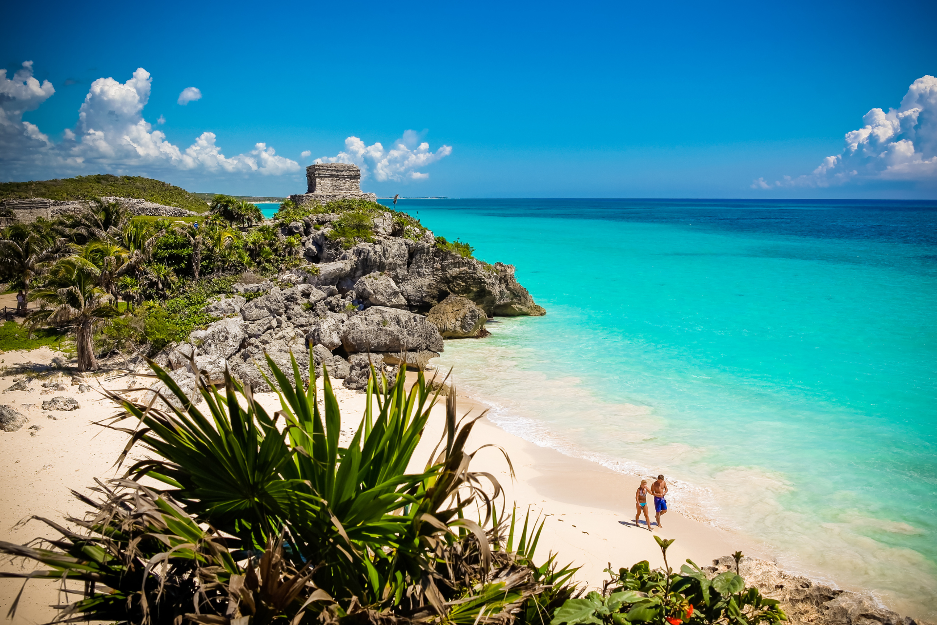 A beautful golden sand beach and clear sea in The Mexican Riviera with a couple walking on the sand